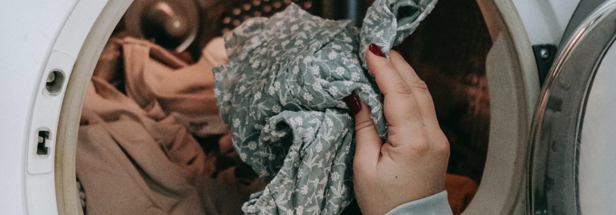 Photo of someone putting clothes in a dryer.